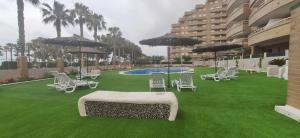 a lawn with chairs and umbrellas and a pool at Costa Marina I, 1ª linea, 4ª planta, Norte in Oropesa del Mar