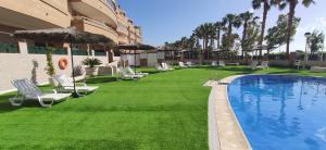 a hotel with a lawn with chairs and a swimming pool at Costa Marina I, 1ª linea, 4ª planta, Norte in Oropesa del Mar