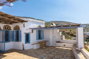 a house with white walls and blue windows and a roof at Sylvia House in Arnados