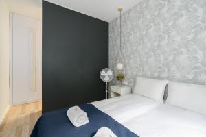 a bedroom with a white bed and a black wall at Poznań City Center Sikorskiego by Renters in Poznań