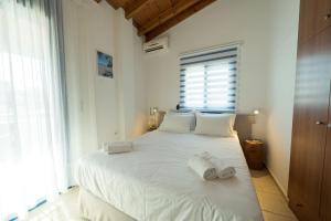 a bedroom with a large white bed with towels on it at Sunset Home Crete in Paránimfoi