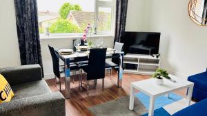a living room with a table with chairs and a television at Spacious and Bright 2 Bedroom Apartment, Sleeps 6, 1st Floor with Free Parking, Business and Leisure by Jesswood Properties in Hinckley