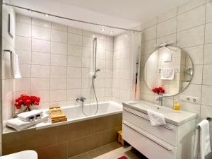 a bathroom with a tub and a sink and a mirror at Stilvolles Apartment «Coco» am Bodensee in Hörbranz