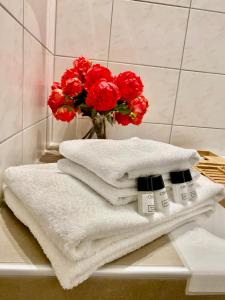 um monte de toalhas numa prateleira com um vaso de flores vermelhas em Stilvolles Apartment «Coco» am Bodensee em Hörbranz