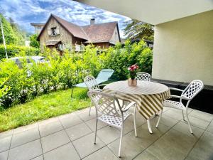 a patio with a table and chairs and a house at Stilvolles Apartment «Coco» am Bodensee in Hörbranz