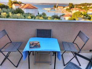 a blue table and chairs on a balcony with a view of the water at Apartman Hanna in Ždrelac