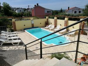 a swimming pool in a yard with chairs and a swimming pool at Maleluni in Malinska
