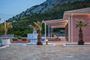 a house with palm trees in front of a mountain at Saint Nicholas Villas 3 in Skala