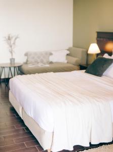 um quarto com uma grande cama branca e um sofá em Althaia Hotel em Thermo