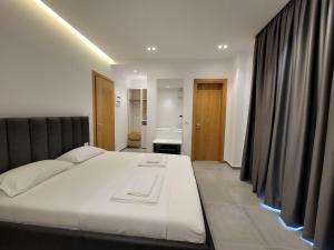 1 dormitorio con 1 cama blanca grande con cortinas negras en Vila Anxhelo en Ksamil