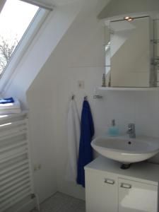 ein Bad mit einem Waschbecken und einem Spiegel in der Unterkunft Ferienwohnung am See, Hage / Norddeich in Hage