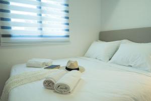 a white bed with towels and a hat on it at Sunset Home Crete in Paránimfoi