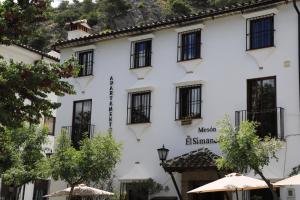 un edificio blanco con ventanas y sombrillas negras en Plaza de los asomaderos 54 Grazalema, en Grazalema