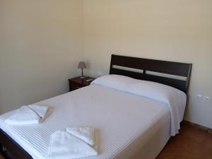 1 dormitorio con 1 cama blanca y 2 toallas en Nereids Apartments-Agavi, en Petalidi