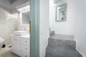 a white bathroom with a sink and a mirror at Amazing View Villa Oia with Jacuzzi in Oia