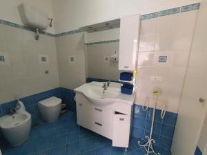 un bagno blu e bianco con lavandino e servizi igienici di Casa Rossella a Procida