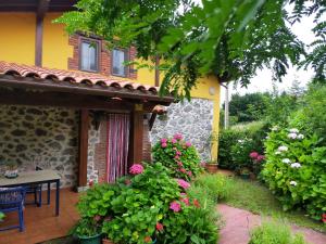 un jardín frente a una casa con flores en La casita de las flores, en Monte Miravalles