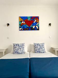 two beds in a room with a painting on the wall at Pirata Milfontes Guest House in Vila Nova de Milfontes