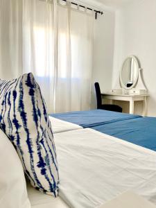 a bed with a blue and white blanket and a mirror at Pirata Milfontes Guest House in Vila Nova de Milfontes