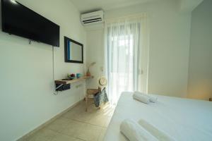 a white bedroom with a bed and a window at Sunset Home Crete in Paránimfoi