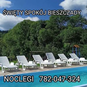 a row of white lounge chairs next to a swimming pool at Święty Spokój Bieszczady 782-047-324 in Ustrzyki Dolne