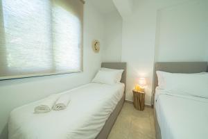 two twin beds in a room with a window at Sunset Home Crete in Paránimfoi