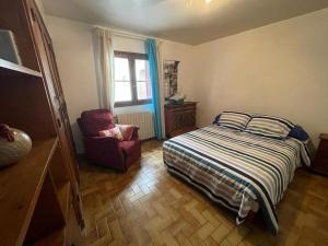 Maison chaleureuse au coeur des Aspres في Camélas: غرفة نوم بسرير وكرسي ونافذة