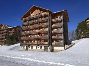 ein großes Apartmenthaus im Schnee mit Schnee in der Unterkunft Vue panoramique tout confort 150m pistes commerces et loisirs in Le Dévoluy