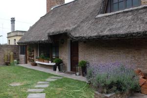 a brick house with a thatched roof and purple flowers at Divina casa en Carrasco con piscina in Montevideo