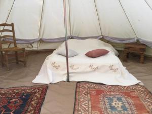 a bed in a tent with two pillows and a chair at EcoCamping d Hacadour in Mellionnec