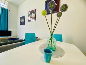 a white table with a vase with flowers in it at Mon indépendant Wifi Parking Terrasse Un-Séjour-à-Part in Florange