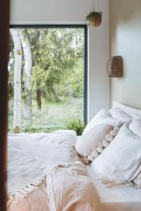 ein Bett mit Kissen und ein Fenster im Schlafzimmer in der Unterkunft River Cabin in Inciems