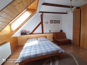sypialnia z łóżkiem i krzesłem na poddaszu w obiekcie Domek i Apartamenty Stokrotka w mieście Krynica Zdrój