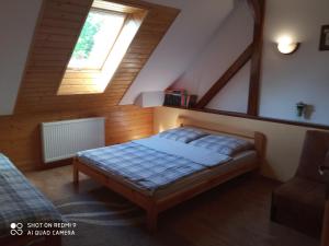 sypialnia z łóżkiem na poddaszu z oknem w obiekcie Domek i Apartamenty Stokrotka w mieście Krynica Zdrój