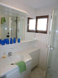 ein weißes Bad mit einem Waschbecken und einer Dusche in der Unterkunft Ferienhäusle Sonnenblume Titisee in Titisee-Neustadt