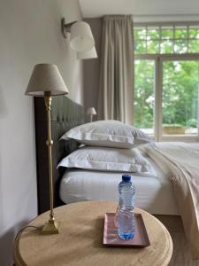 uma garrafa de água sentada numa mesa ao lado de uma cama em La Vigie, Spa em Spa