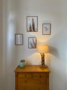 a lamp on a wooden dresser with pictures on the wall at Appartement proche des remparts et tous commerces. in Montreuil-sur-Mer