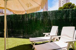 貝尼多姆的住宿－Apartamento Loft con terreno privado y parking compartido - a 800m de Playa Poniente，围栏旁的两把椅子和一把伞