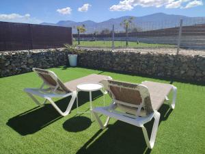 2 chaises et une table sur l'herbe dans l'établissement Apartamento Buenavista con jacuzzi y jardín privado en Abadia, à Abadía