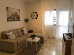 a living room with a couch and a clock on the wall at Exclusive Las Gavias in Las Lagunas