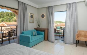 a bedroom with a blue chair and a balcony at Sivota Hotel in Sivota