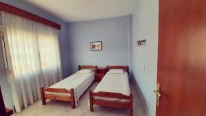 2 Betten in einem Zimmer mit Fenster und Tür in der Unterkunft ERATO in Leptokaryá