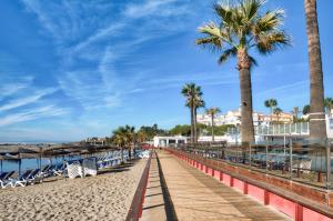 a boardwalk on a beach with palm trees and chairs at PLAYAS DEL DUQUE, PUERTO BANUS, GOLF .PLAYA Y COMPRAS in Marbella