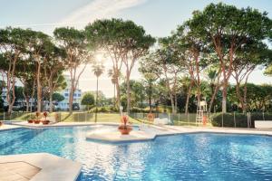 una piscina con palmeras en un parque en PLAYAS DEL DUQUE, PUERTO BANUS, GOLF .PLAYA Y COMPRAS, en Marbella