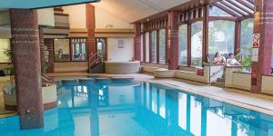 a swimming pool in a building with people standing around it at Riverside Cottage 6 guests 4 adults max hot tub in Backbarrow