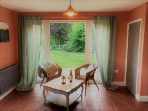 sala de estar con mesa, sillas y ventana en Large House On Farm With Own Heated Pool, As Seen On BBC TV, en Cullompton