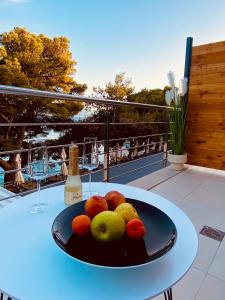 a bowl of fruit on a table with a bottle of wine at Zlatni Rat Beach Resort in Bol