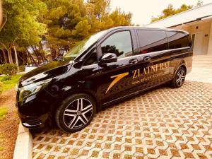 a black van parked in front of a house at Zlatni Rat Beach Resort in Bol