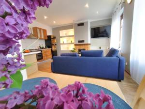 sala de estar con sofá azul y flores púrpuras en Apartament Kominek en Giżycko