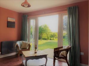 - un salon avec une table et une grande fenêtre dans l'établissement Large House On Farm With Own Heated Pool, As Seen On BBC TV, à Cullompton